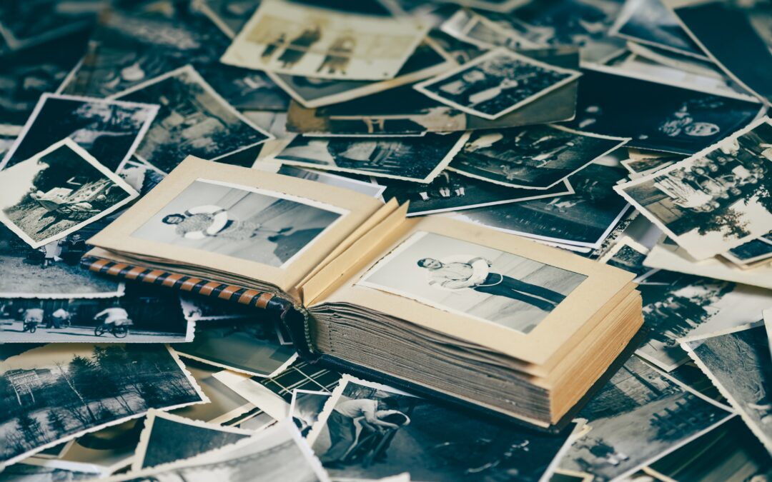 zdjęcie albumy ze starymi fotografiami, leżącego na rozsypanych czarno-białych fotografiach
